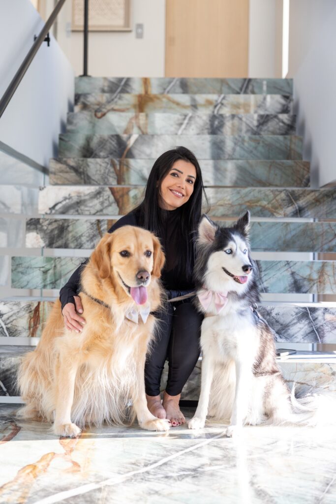 Asal Almawy on a marble staircase with her golden retriever and husky