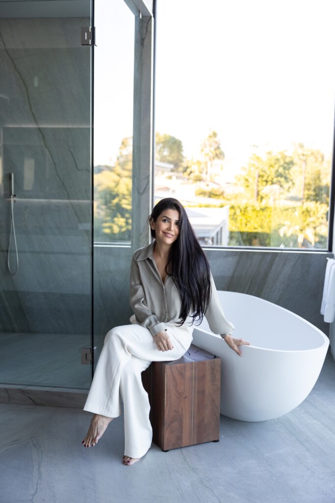 Asal Almawy seated in a bright bathroom with a garden view